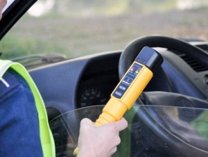 policjant trzyma urządzenie Alcoblow służące do badania trzeźwości.