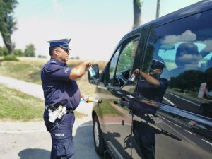 policjant rozdaje ulotkę kierującemu busem