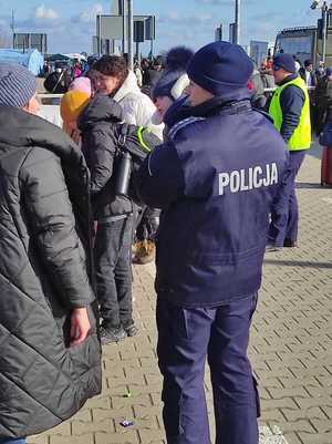 Policjantka z dzieckiem na ręku, rozmawia z kobietą.