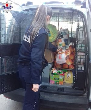 Policjantka pakuje do pojazdu produkty dla potrzebujących