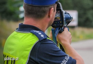 Umundurowany policjant mierzący prędkość z jaką poruszają się pojazdy