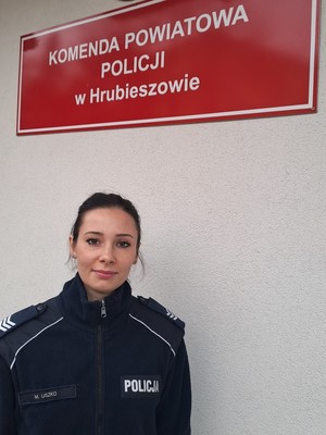 Umundurowana policjantka sierżant sztabowy Małgorzata Uszko. w tle napis Komenda Powiatowa Policji w Hrubieszowie