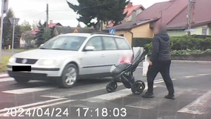 Mężczyzna z dzieckiem w wózku przechodzi przez oznakowane przejście dla pieszych