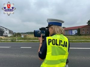 policjantka mierzy prędkość nadjeżdżających pojazdów na drodze