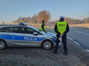 Policjant Wydziału Ruchu Drogowego stoi przy oznakowanym radiowozie