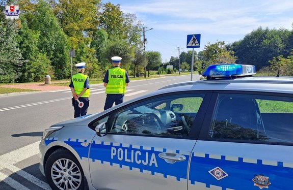policjanci ruchu drogowego stojący przy radiowozie podczas kontroli drogowej