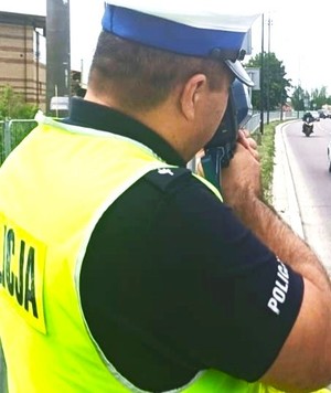 policjant Wydziału Ruchu Drogowego mierzy prędkość jazdy nadjeżdżających pojazdów