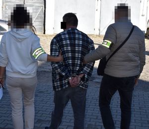 policjanci prowadzą zatrzymanego mężczyznę zakutego w kajdanki