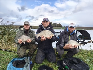 trzech mężczyzn trzyma w dłoniach ryby