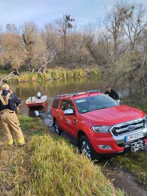 samochód straży pożarnej przy rzece Bug obok funkcjonariusze straży pożarnej