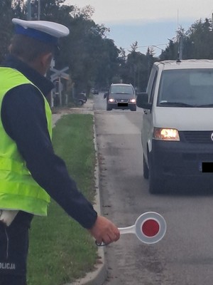 umundurowany policjant zatrzymuje nadjeżdżający pojazd za pomocą tarczy do zatrzymywania