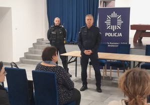 Zdjęcie przedstawia dwóch umundurowanych policjantów w trakcie debaty społecznej w Strzyżowie
