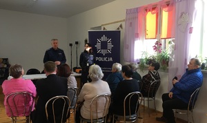 Zdjęcie przestawia dwóch umundurowanych policjantów uczestniczących w debacie społecznej z mieszkańcami Hrubieszowa