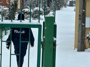 umundurowany policjant idzie po ośnieżonej posesji