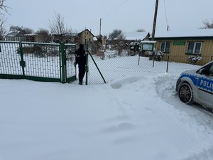 umundurowany policjant chodzi po ośnieżonej posesji