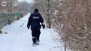 Umundurowany policjant idzie po zaśnieżonej ścieżce