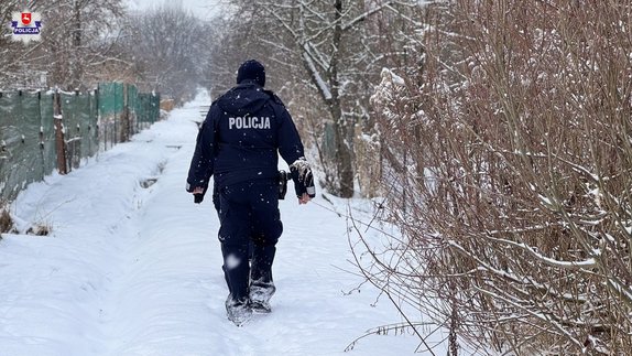 Umundurowany policjant idzie po zaśnieżonej ścieżce