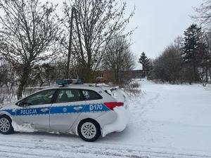 radiowóz policyjny stoi  przy zaśnieżonej posesji
