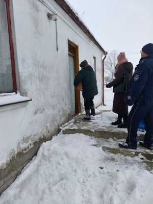 policjant z pracownikami opieki społecznej puka do drzwi domu