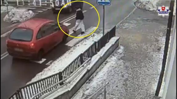 Ujęcie z kamery na którym widać młodą kobietę przechodzącą przez przejście dla pieszych.