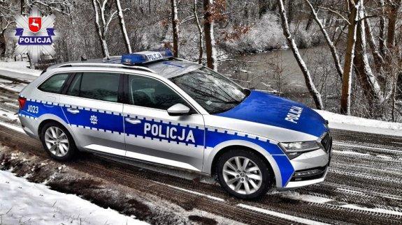 radiowóz policyjny jadący po zaśnieżonej jezdni