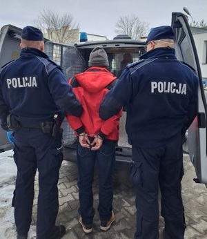 Policjanci przy radiowozie z zatrzymanym