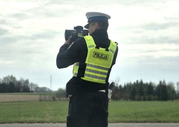 umundurowany policjant mierzy prędkość nadjeżdżających pojazdów