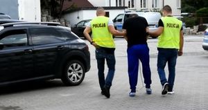 mężczyzna w kajdankach doprowadzany policjantów