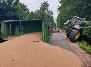 wysypane z przyczepy zboże na drodze, ciągnik w rowie